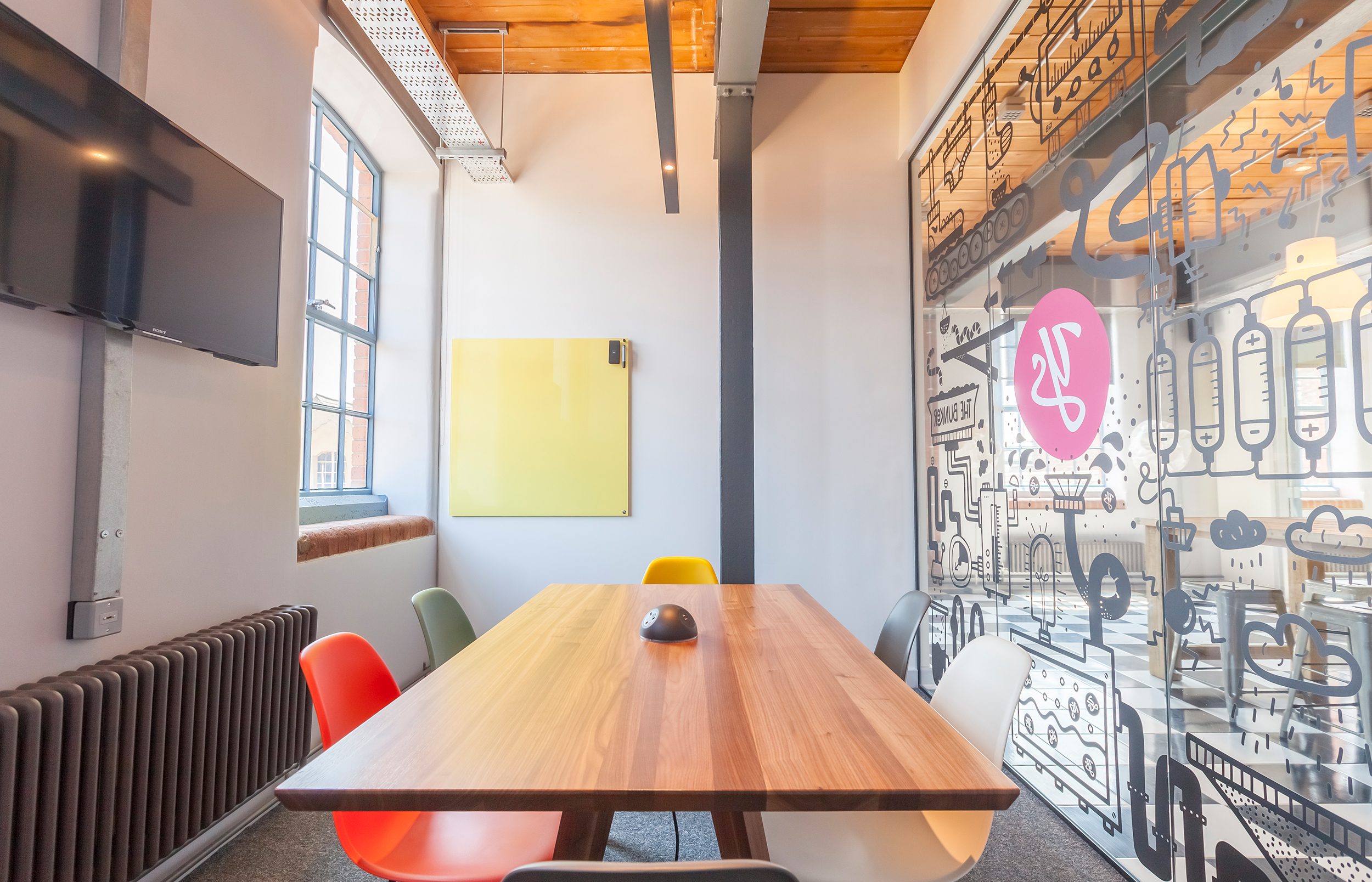 The Bunker has a beautiful glass wall, bright windows, a magnetic glass drawing board, and large TV screen.